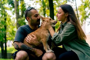 portrait of a young couple in love walking in the park with their pet kissing him love for dogs care romance